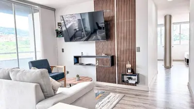 a living room with a couch and a tv on a wall at Plaza Corales Manizales in Manizales