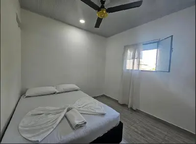 a white bedroom with a bed with a ceiling fan at Apartahotel in Doradal