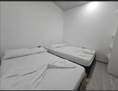 two beds in a room with white walls at Apartahotel in Doradal
