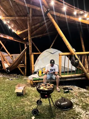 a man sitting in front of a tent with a grill at Conexión naturaleza in San Luis