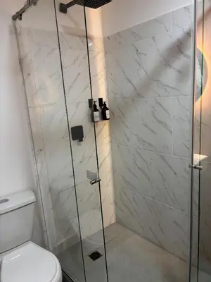 a shower with a glass door next to a toilet at Moore 45 Tu Espacio Comodo en Medellín in Medellín