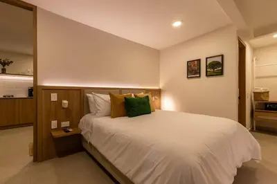 a bedroom with a large white bed with green pillows at 202 Modern Stay in Laureles Area Cozy Balcony AC in Medellín