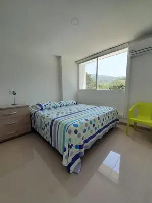 a white bedroom with a bed and a window at Agradable y confortable apto vacacional en Santa Fé de Antioquia-Colombia dentro de condominio con piscina, tobogán, zonas recreativas, jardines y espectacular vista in Santa Fe de Antioquia