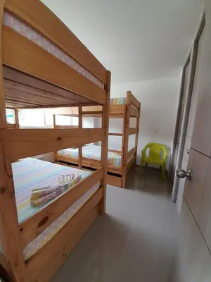 a bedroom with two bunk beds and a yellow chair at Agradable y confortable apto vacacional en Santa Fé de Antioquia-Colombia dentro de condominio con piscina, tobogán, zonas recreativas, jardines y espectacular vista in Santa Fe de Antioquia