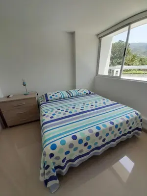 a bed in a bedroom with a window at Agradable y confortable apto vacacional en Santa Fé de Antioquia-Colombia dentro de condominio con piscina, tobogán, zonas recreativas, jardines y espectacular vista in Santa Fe de Antioquia