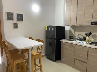 a kitchen with a white table and a black refrigerator at Las Flores de María 302 in Jardin