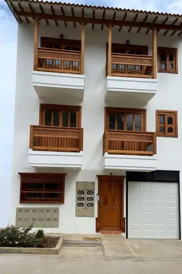 a white building with wooden balconies and a garage at Las Flores de María 302 in Jardin