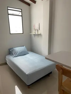 a small bedroom with a bed and a table at Las Flores de Mria 303 in Jardin