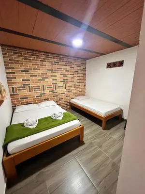 a bedroom with two beds and a brick wall at Hotel Kapla in San Rafael
