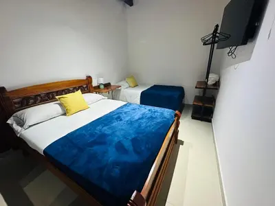 two beds in a room with a tv on the wall at Hotel Jardin de Rosas in Jardin
