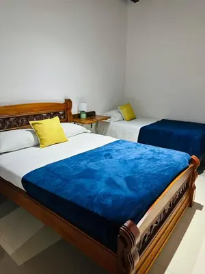 a bedroom with two beds with blue sheets at Hotel Jardin de Rosas in Jardin