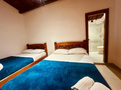 two beds in a room with a bathroom at Hotel Jardin de Rosas in Jardin