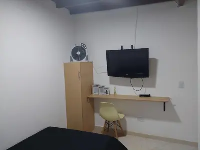 a bedroom with a desk with a television and a chair at Single studio apartment 4 in Medellín