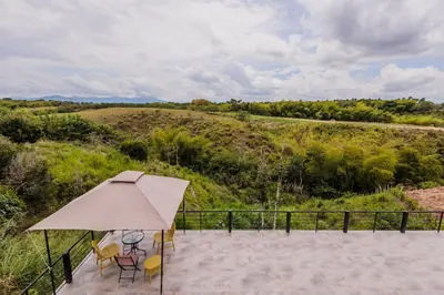 a patio with an umbrella and chairs and a field at Luxury Villa in Cerritos ride horses nearby in Pereira