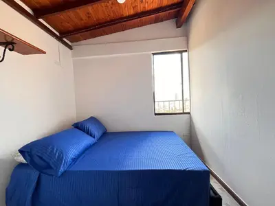 a small room with a blue bed with a window at Apartment near downtown in Medellín