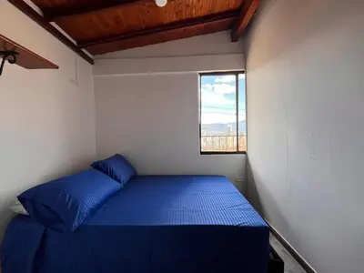 a small bedroom with a blue bed and a window at Apartment near downtown in Medellín