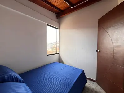 a small bedroom with a blue bed and a window at Apartment near downtown in Medellín