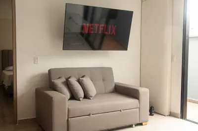 a couch with two pillows in a living room at Frente al mall Viva Envigado, AC, moderno in Envigado