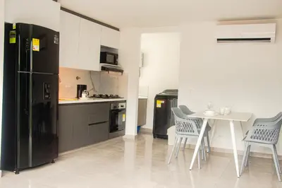 a kitchen with a black refrigerator and a table and chairs at Frente al mall Viva Envigado, AC, moderno in Envigado