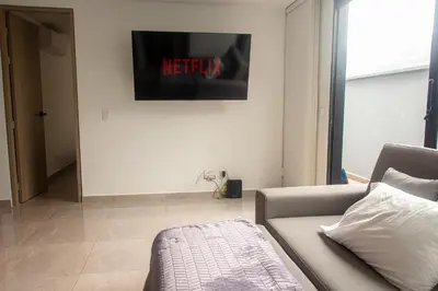 a living room with a couch and a tv on the wall at Frente al mall Viva Envigado, AC, moderno in Envigado