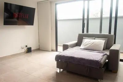 a room with a bed and a chair in front of a window at Frente al mall Viva Envigado, AC, moderno in Envigado