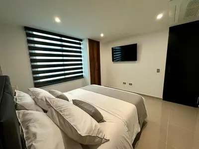 a bedroom with a bed with white sheets and pillows at Rooca Urban in Medellín