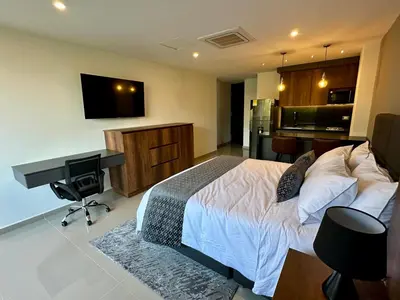 a bedroom with a bed and a desk and a computer at Rooca Urban in Medellín