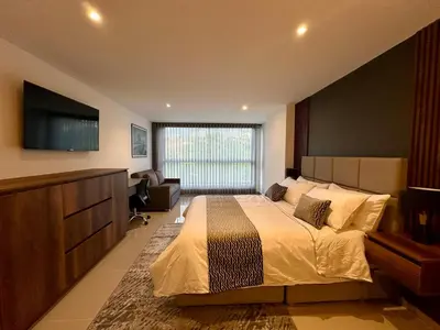 a bedroom with a large bed and a flat screen tv at Rooca Urban in Medellín