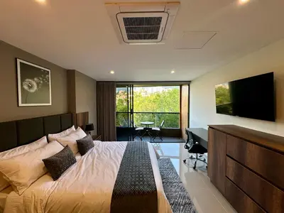 a bedroom with a bed and a television and a desk at Rooca Urban in Medellín
