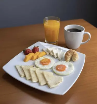 a plate with eggs and fruit and a cup of coffee at Rooca Urban in Medellín
