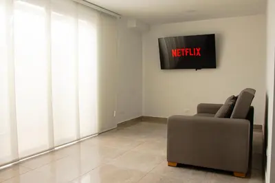a living room with a couch and a tv on the wall at Frente a Viva Envigado, AC, moderno e iluminado in Envigado