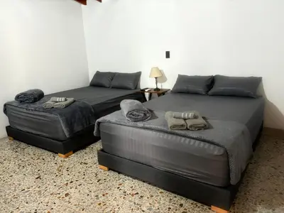 two beds and a ottoman in a bedroom at CASA GAMA Your spring in Medellín in Medellín