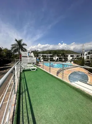 a balcony with a swimming pool with green grass at Apartasol santafe live in Santa Fe de Antioquia