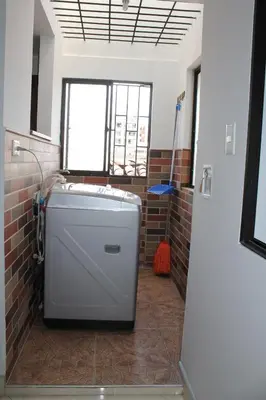 a bathroom with a refrigerator in a room with a brick wall at Acogedor Apartamento en la ciudad de Medellín- La floresta in Medellín