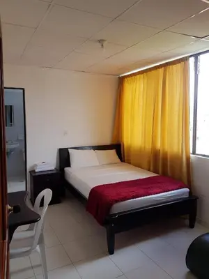 a bedroom with a bed with a yellow curtain at Hotel Galerias in Ruiosucio