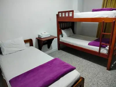 two bunk beds in a room with purple sheets at Hotel Galerias in Ruiosucio