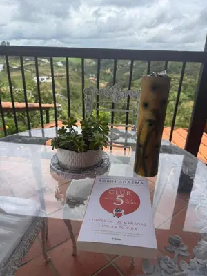 a glass table with a book and a vase on a balcony at Encantadora finca en el corazón de Marinilla con vistas únicas y ubicación privilegiada in Marinilla