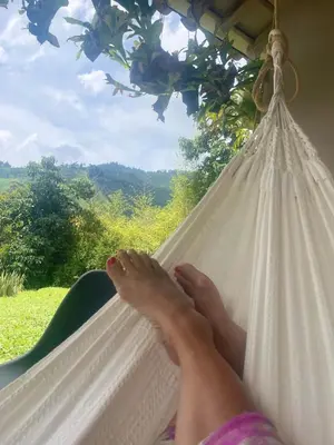 a woman laying on a hammock with her feet on a window at Casa de Campo Cerca a Medellín in Angelópolis