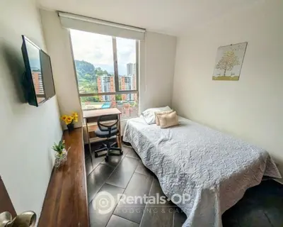a bedroom with a bed and a desk and a window at Spacious apartment near Lleras and Provenza rentalsOP AN08 in Medellín