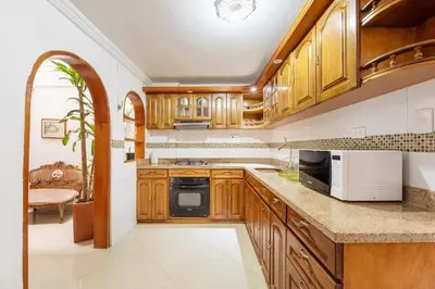 a kitchen with wooden cabinets and white appliances at Spacious House with Garden & View over Medellin in Medellín