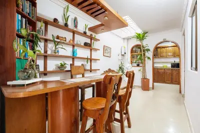 a kitchen with a wooden bar and chairs at Spacious House with Garden & View over Medellin in Medellín