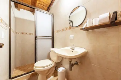 a bathroom with a toilet and a sink and a mirror at Spacious House with Garden & View over Medellin in Medellín