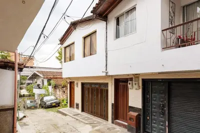 a white house with doors and a car parked outside at Spacious House with Garden & View over Medellin in Medellín