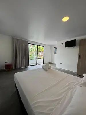 a bedroom with a large white bed and a television at Casa Bosque Vivo in Norcasia