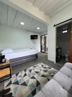a bedroom with a bed and a couch and a tv at Casa Bosque Vivo in Norcasia