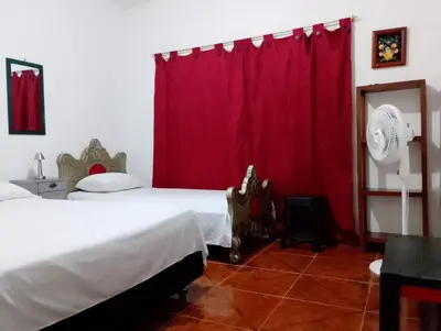 a bedroom with a bed and a red curtain at Casa Sol y Río in Honda