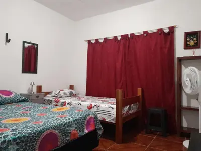 a bedroom with two beds and a red curtain at Casa Sol y Río in Honda