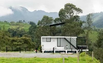 a small white house in a field with trees at Glamping La Maestranza con desayuno incluido in Estación El Salto