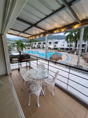 a balcony with a table and chairs and a pool at Apartasol por días en condominio ciudadela Santa Fe de Antioquia in Santa Fe de Antioquia