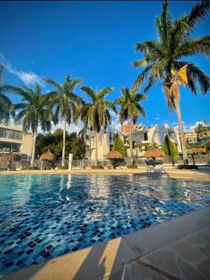 a swimming pool with palm trees in a resort at Apartasol por días en condominio ciudadela Santa Fe de Antioquia in Santa Fe de Antioquia